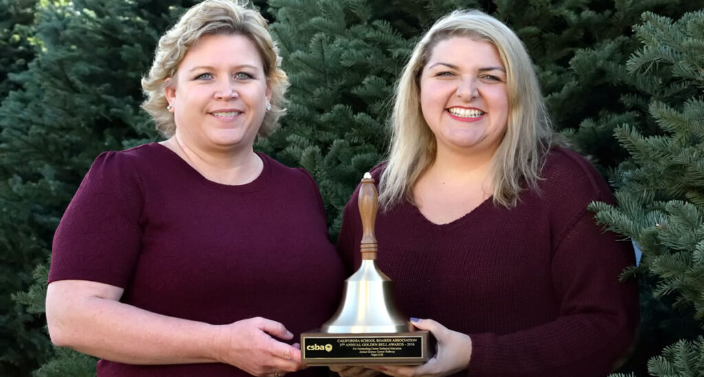 2 Women Holding Golden Bell Award