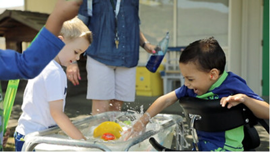 Two boys playing at water table